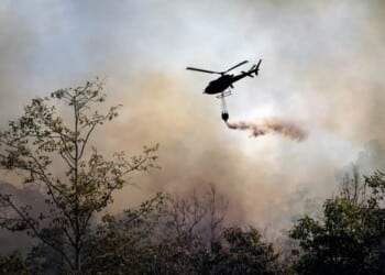 Fire fighting helicopter dropping water onto wildfire